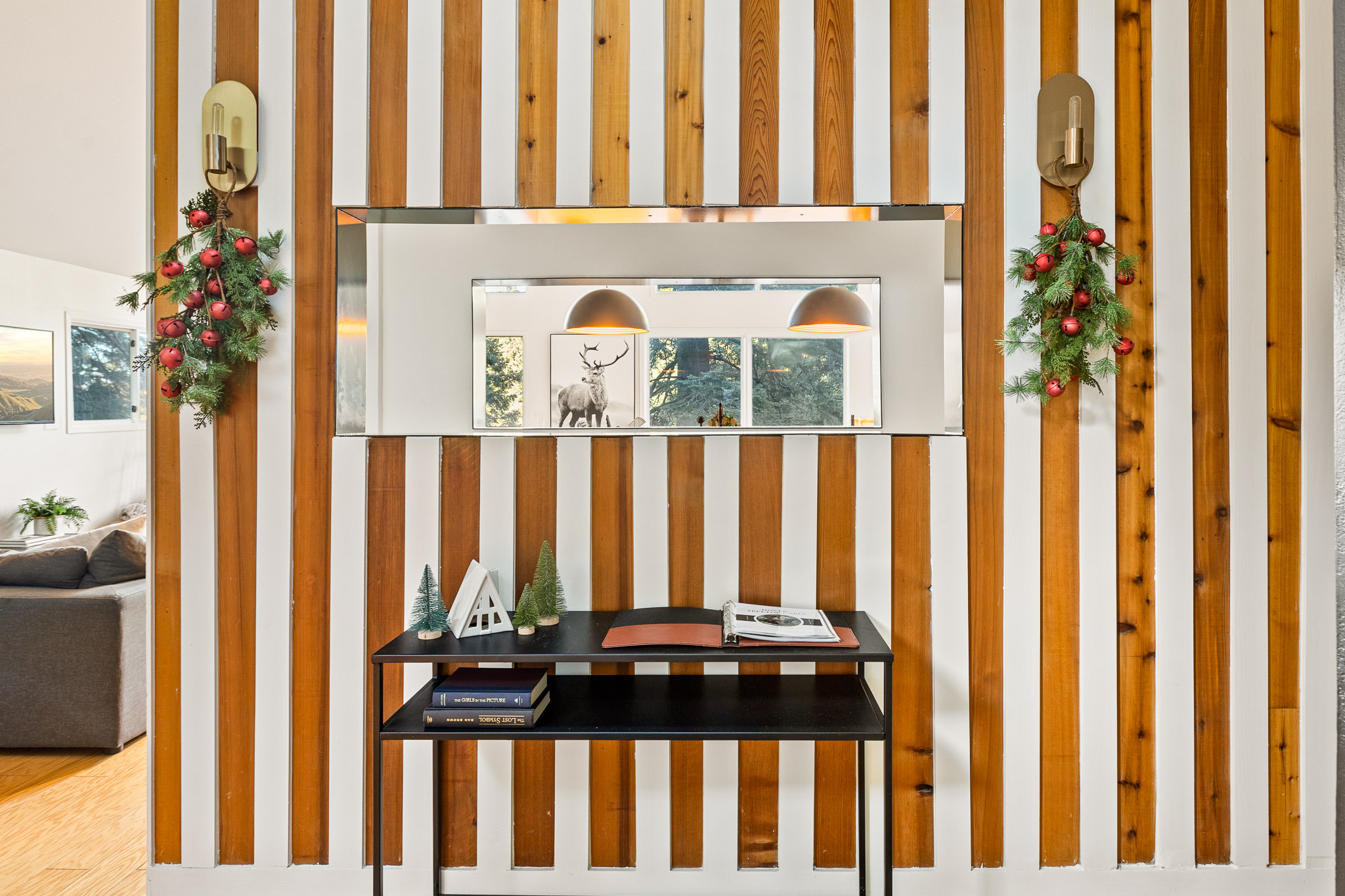 Cozy holiday-ready cabin entry with warm lighting, festive decor, and a modern wood accent wall—perfect for a winter getaway in Lake Arrowhead.