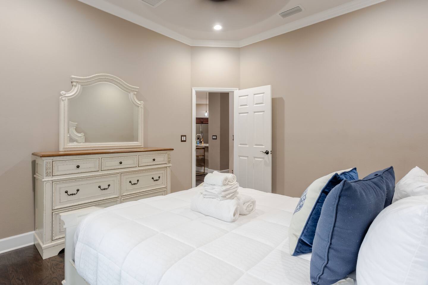 Elegant guest bedroom featuring a plush, inviting bed, sophisticated furnishings, and a spacious dresser for convenient storage—creating a refined, comfortable retreat for a restful stay.
