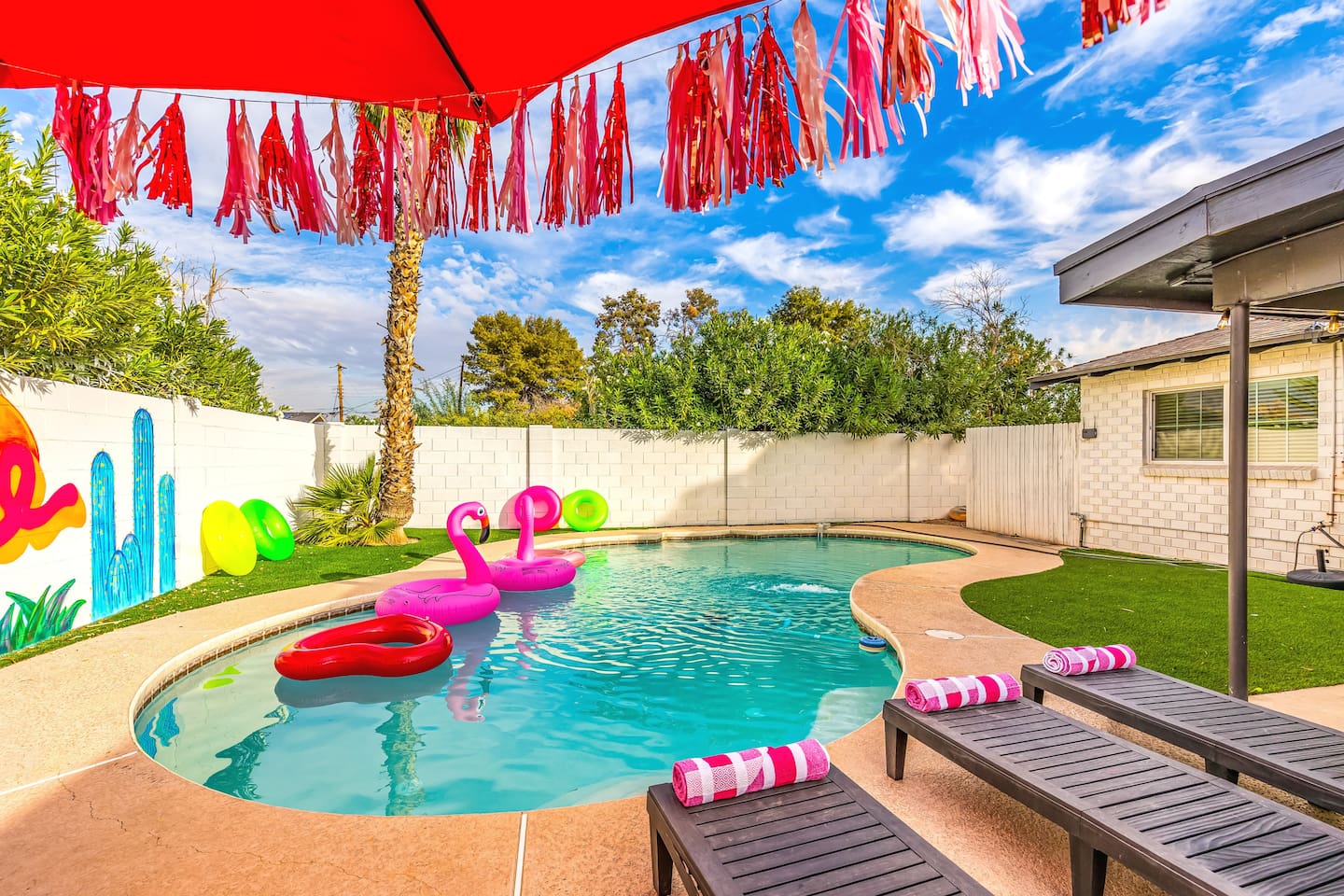 Soak up the Arizona sunshine on sleek loungers by the pool, shaded by a festive red umbrella and surrounded by vibrant greenery.

