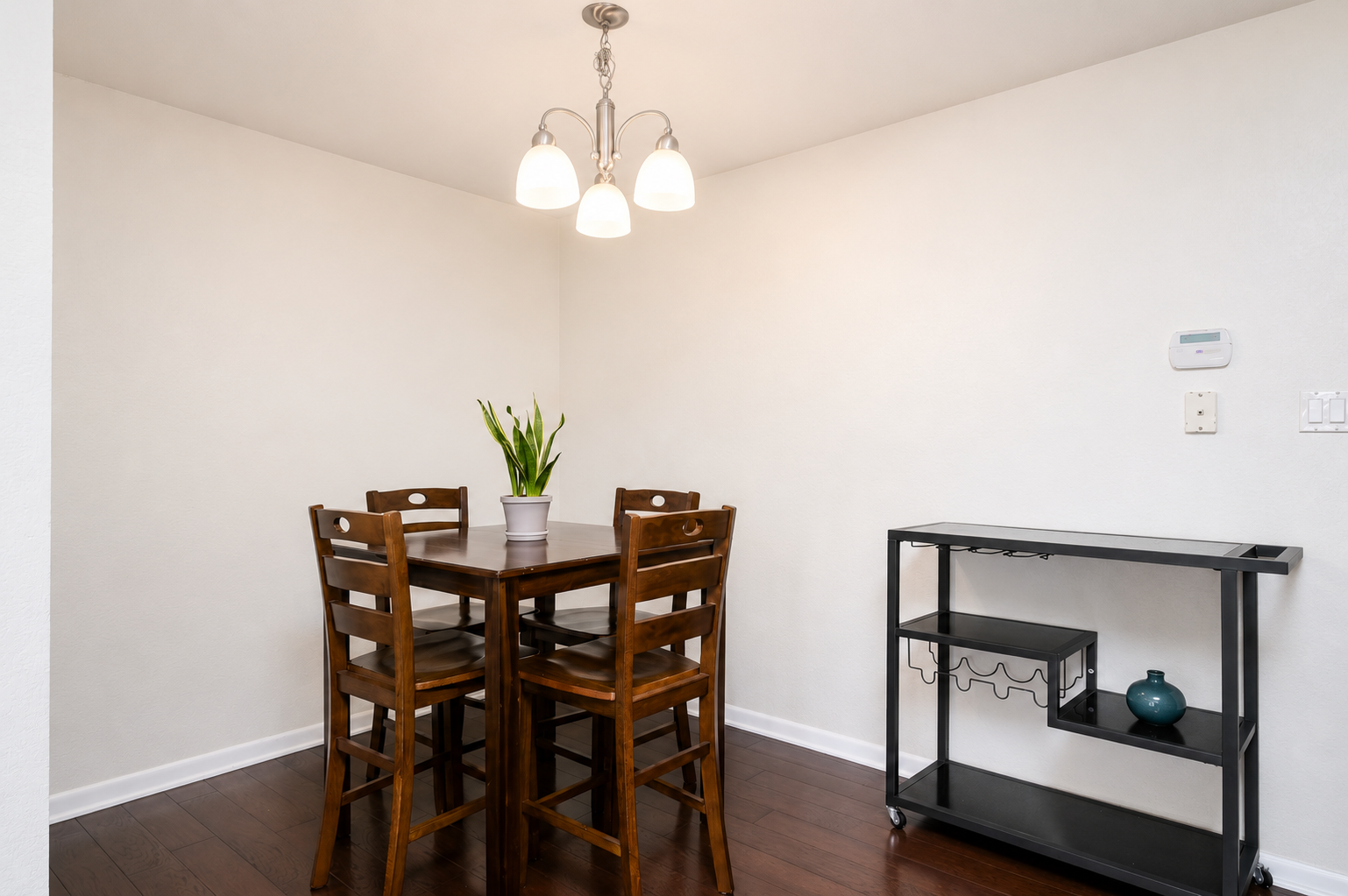 Simple dining setup with seating for four and a nearby storage cart for added convenience.