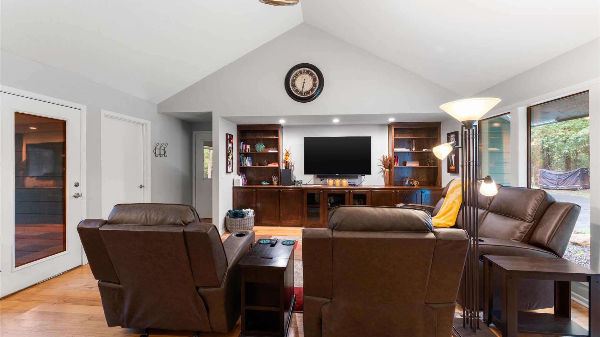 Living room features a reclining couch, recliners, a bistro table, and a wet bar with a refrigerator and ice maker. A 65" TV and plenty of cozy throws make it perfect for relaxing.