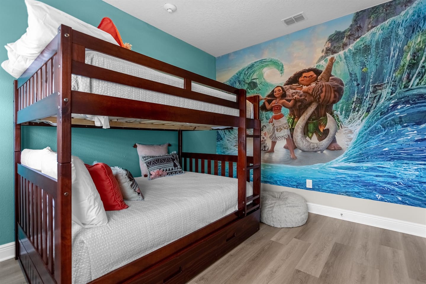 Vibrant Moana-themed room with full-over-full bunk beds and twin trundles, accommodating up to five guests, designed to inspire adventure with its tropical decor and oceanic elements.