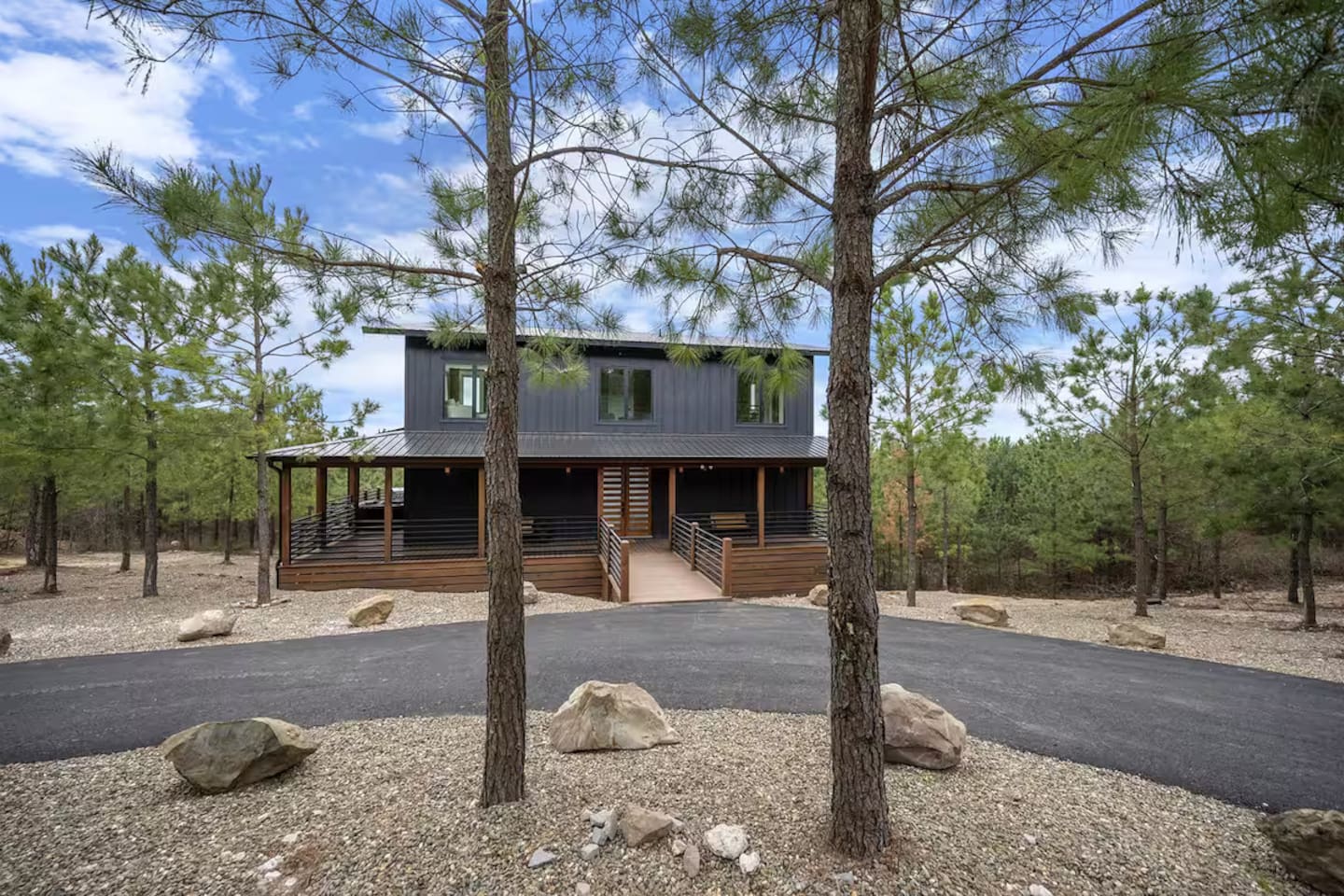 Front exterior with private driveway and wooded surroundings.