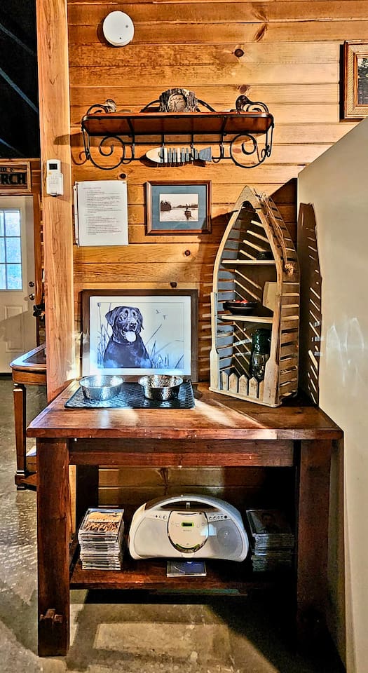This thoughtful corner welcomes both guests and pups, featuring a framed Labrador print, pet bowls, rustic shelf, CD player, and local music. Lodge details and vintage charm set the tone for a stay that’s both comfortable and full of heart.