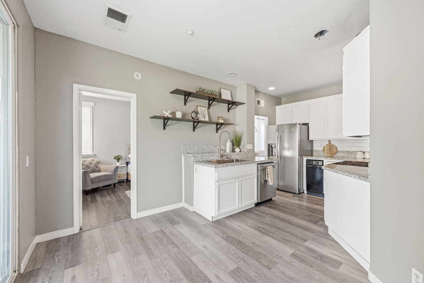 Fully equipped kitchen with stainless refrigerator, dishwasher, coffee maker, toaster, and cooking essentials. Open layout connects to dining area. Oxnard beach house sleeps 10.
