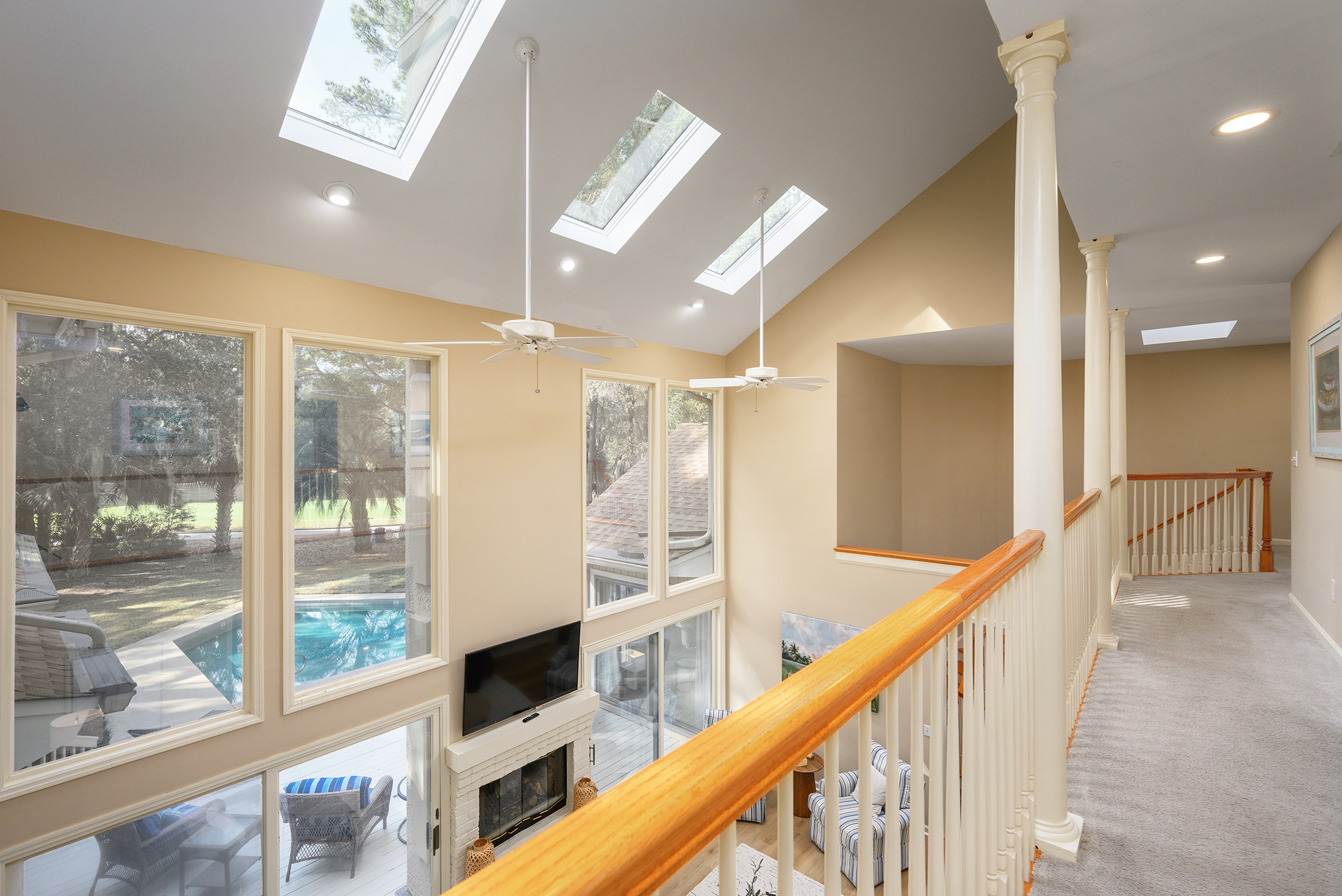 View from upstairs hallway to living room below and out to pool and 11th green