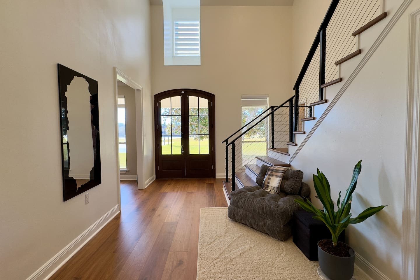 dark wooden front door with glass panels and a tall window above fills the entryway with natural light.
