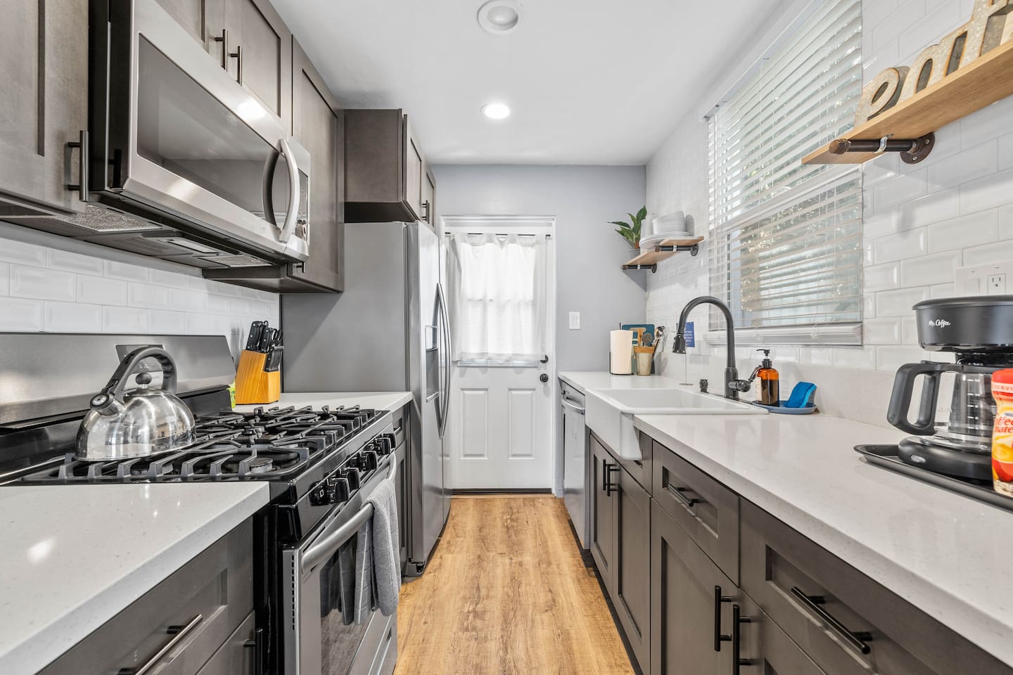 Step into our spacious kitchen, equipped with a stylish sink, stove with microwave, and modern refrigerator. The open layout offers a lovely view of the cozy dining table and inviting living room for a connected living experience.