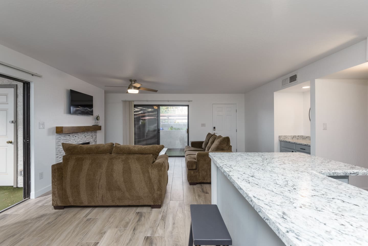 Living room and kitchen view with comfy seating, patio doors, and plenty of counter space nearby.
