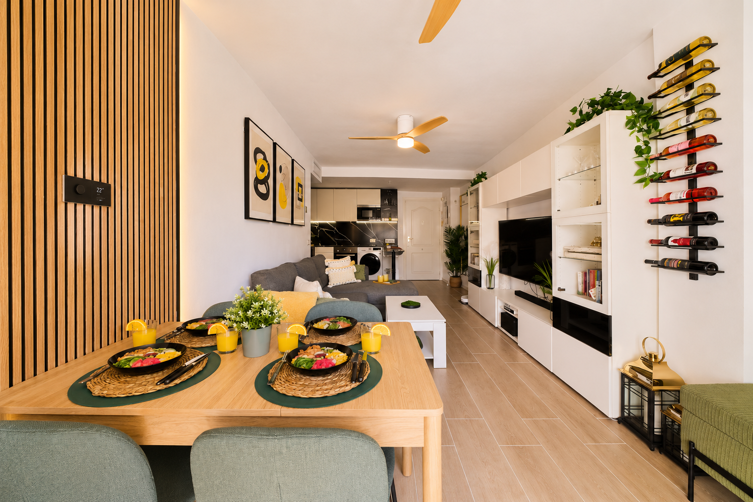 Stylish open-plan living room with a modern kitchen, smart TV, and natural light throughout — ideal for relaxing or sharing a glass of wine after a day by the beach.