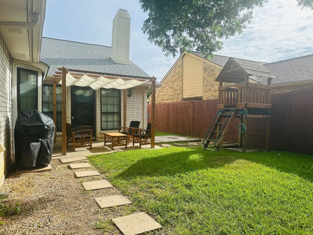 Private backyard with shaded seating and playset — ideal for family fun.