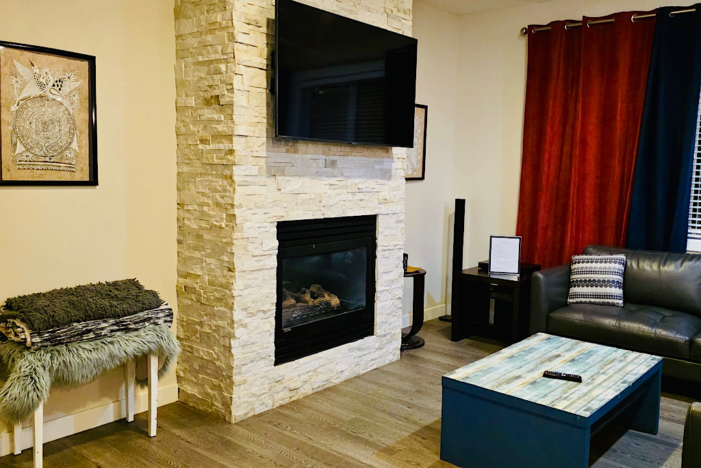 Cozy living room with stone fireplace, smart TV, and plush seating.