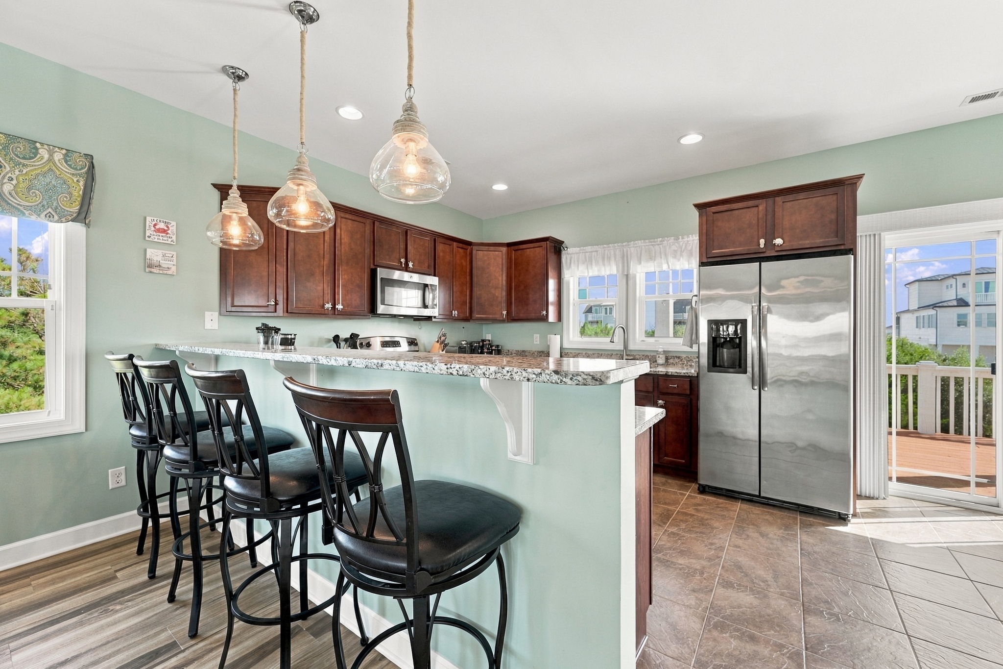 Bright, open kitchen featuring granite countertops, stainless steel appliances, and breakfast bar seating