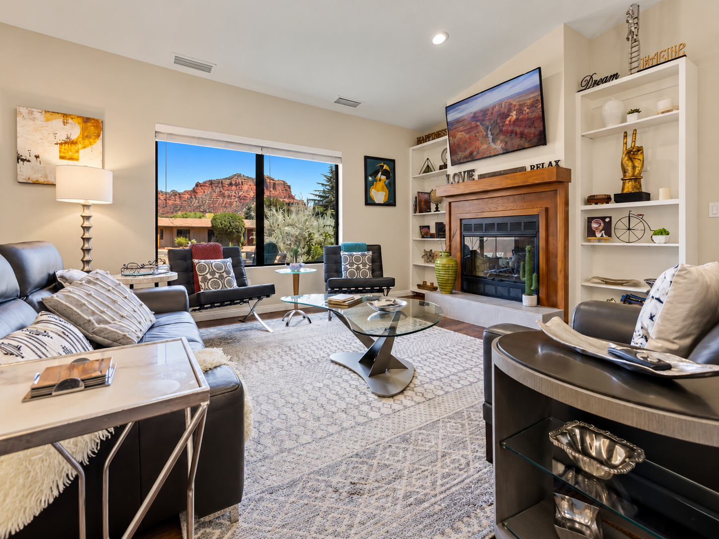 A bright living room with comfortable seating, a fireplace, and Sedona red-rock scenery.