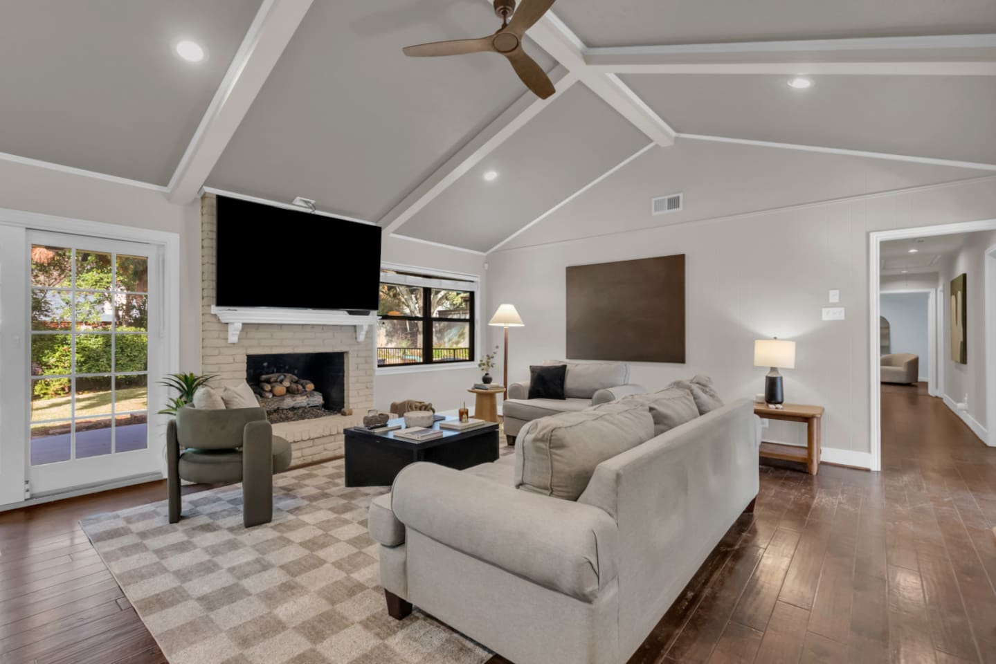Living room featuring a 70” Smart TV, ample seating, a cozy fireplace, and views overlooking the private backyard.