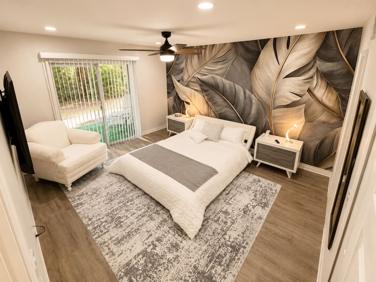 Spacious bedroom featuring a queen bed, reading chair, and direct patio access.