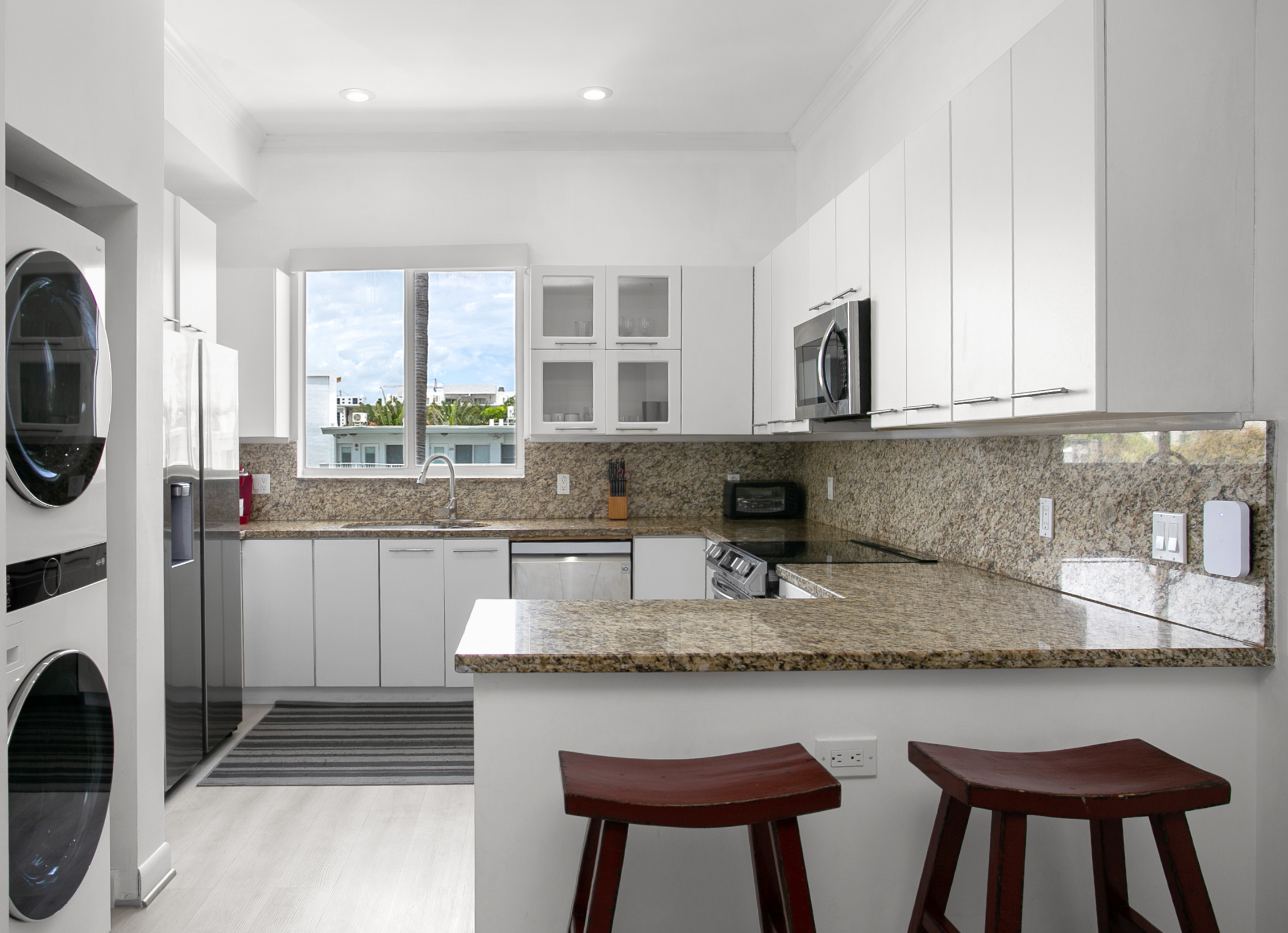 Chef's kitchen with dual-basin sink and breakfast counter. LG laundry tower right next to it.