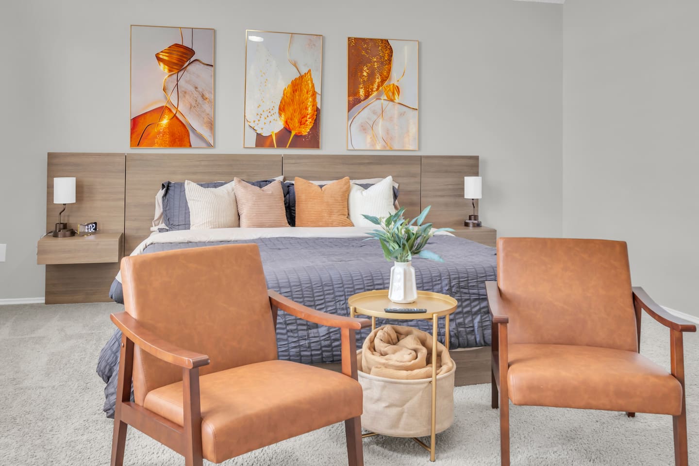 Quiet and private primary suite offering a king bed, sitting area, room-darkening shades, ceiling fan, modern artwork, ample storage, fresh linens, and a peaceful space to unwind.