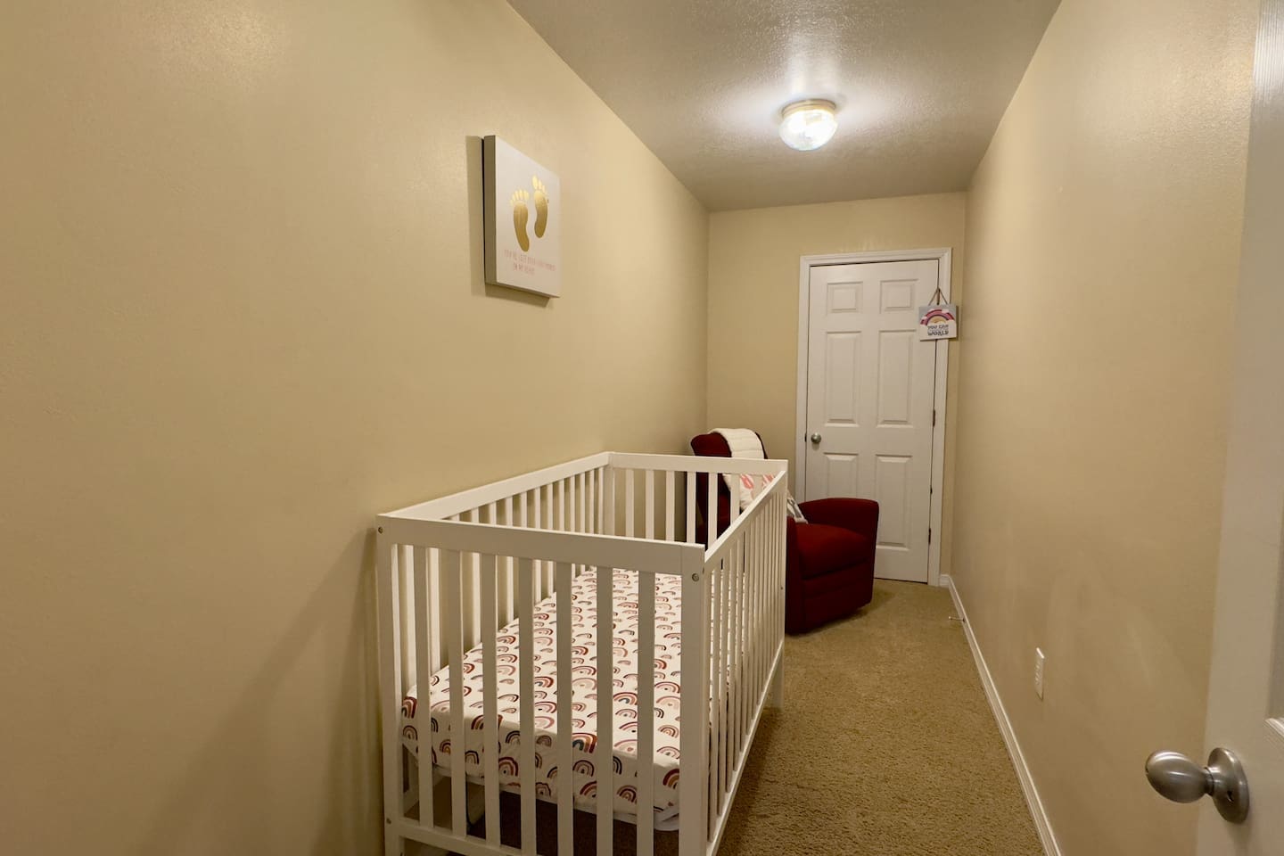 A white crib with patterned bedding sits against soft beige walls, creating a gentle, welcoming space for little ones.