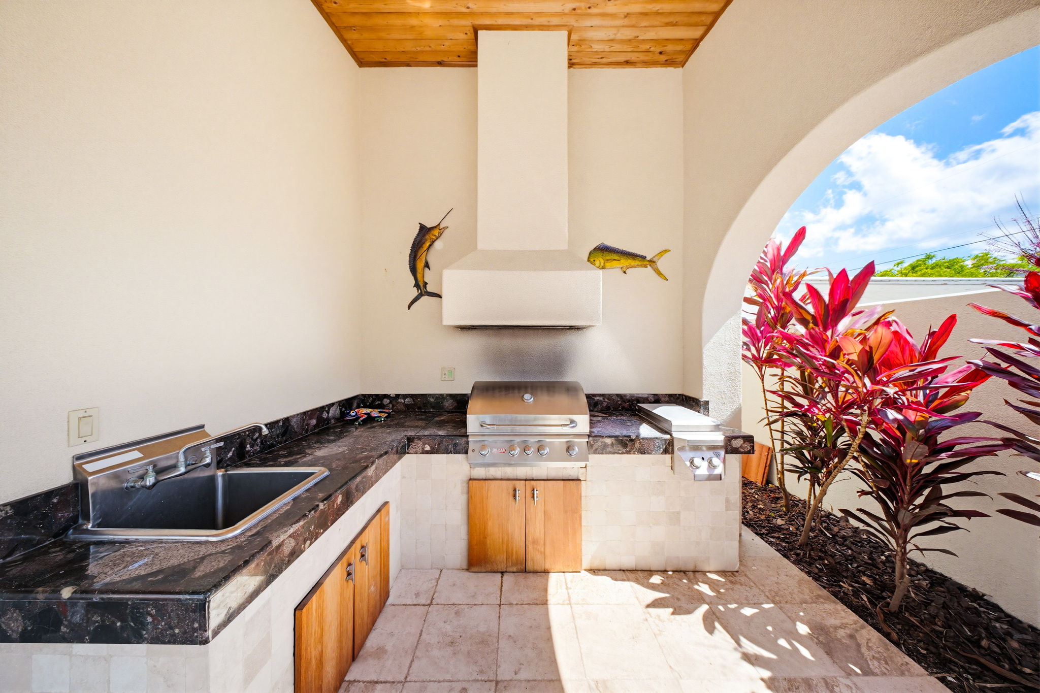 An outdoor kitchen, complete with a built in grill and range hood.