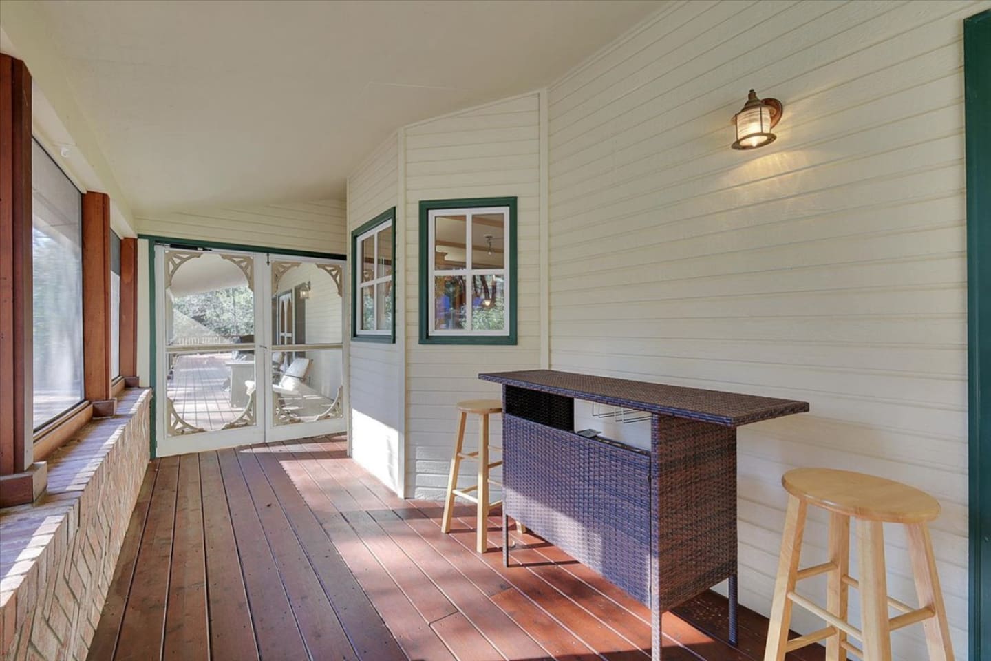 Sunroom bar area with stool seating, wood floors, and a relaxing view toward the outdoor space.
