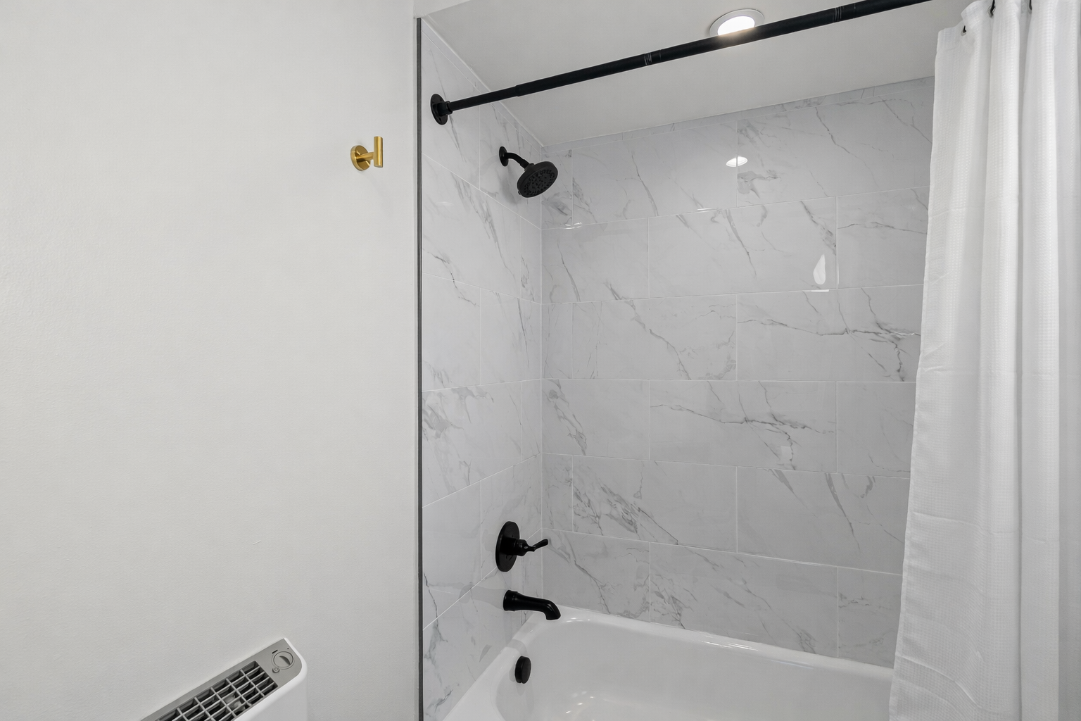 Sleek tub-shower combo with modern tile, matte black fixtures, and a clean, spa-like feel—perfect for unwinding after a long day.