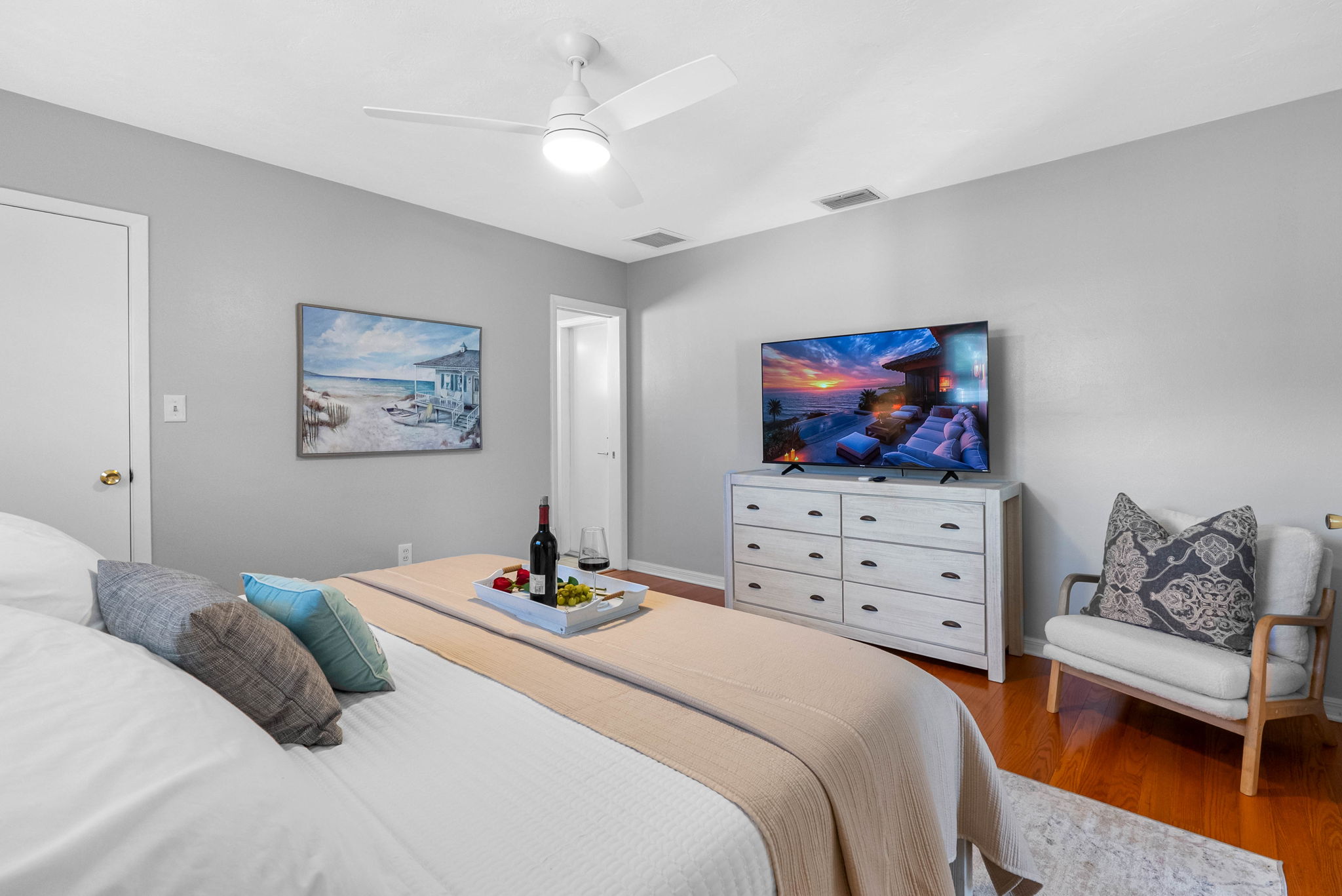 Sleep like royalty in this spacious master bedroom with hardwood floors, warm lighting, and a cozy ambiance.