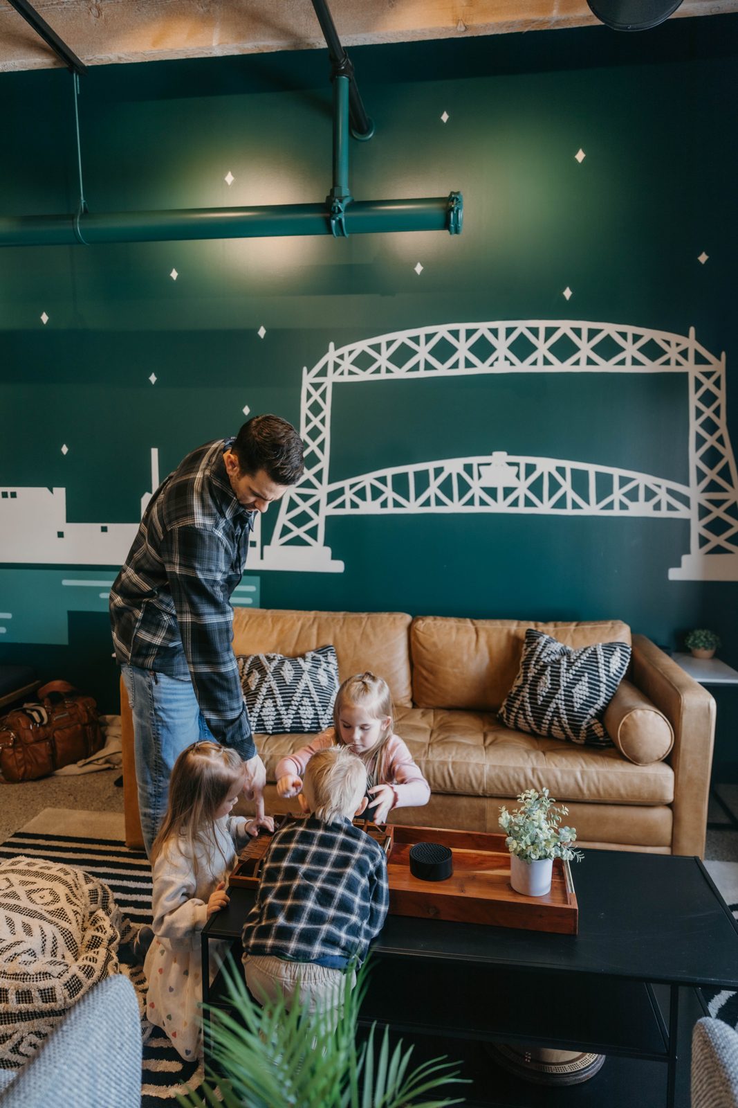 A family relaxing in a Brix condo with an Aerial Lift Bridge mural on the wall in Canal Park, Duluth