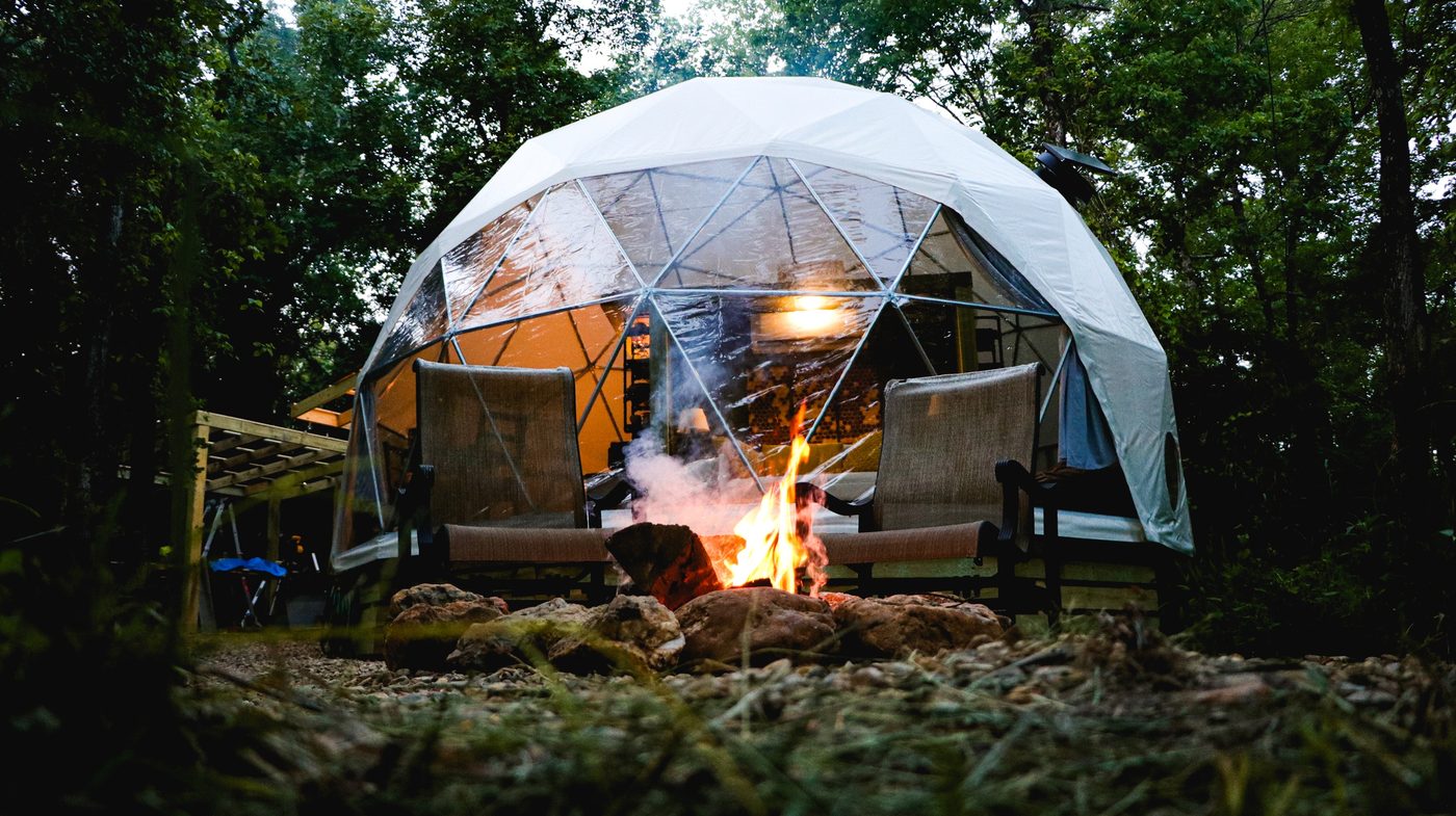 A fire pit glowing in front of The Honey Dome at night in Hochatown