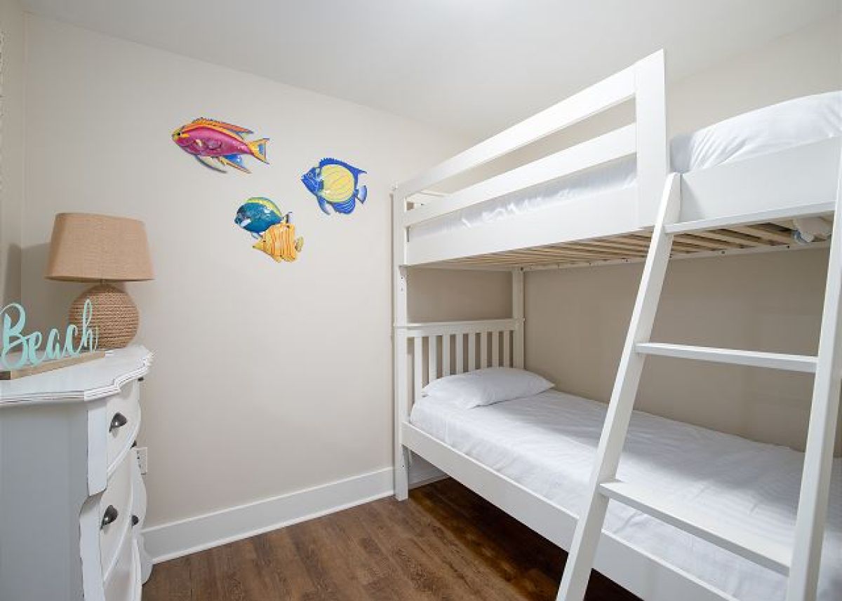 Second bedroom with twin-over-twin bunk bed, dresser, lamp and tropical fish wall art