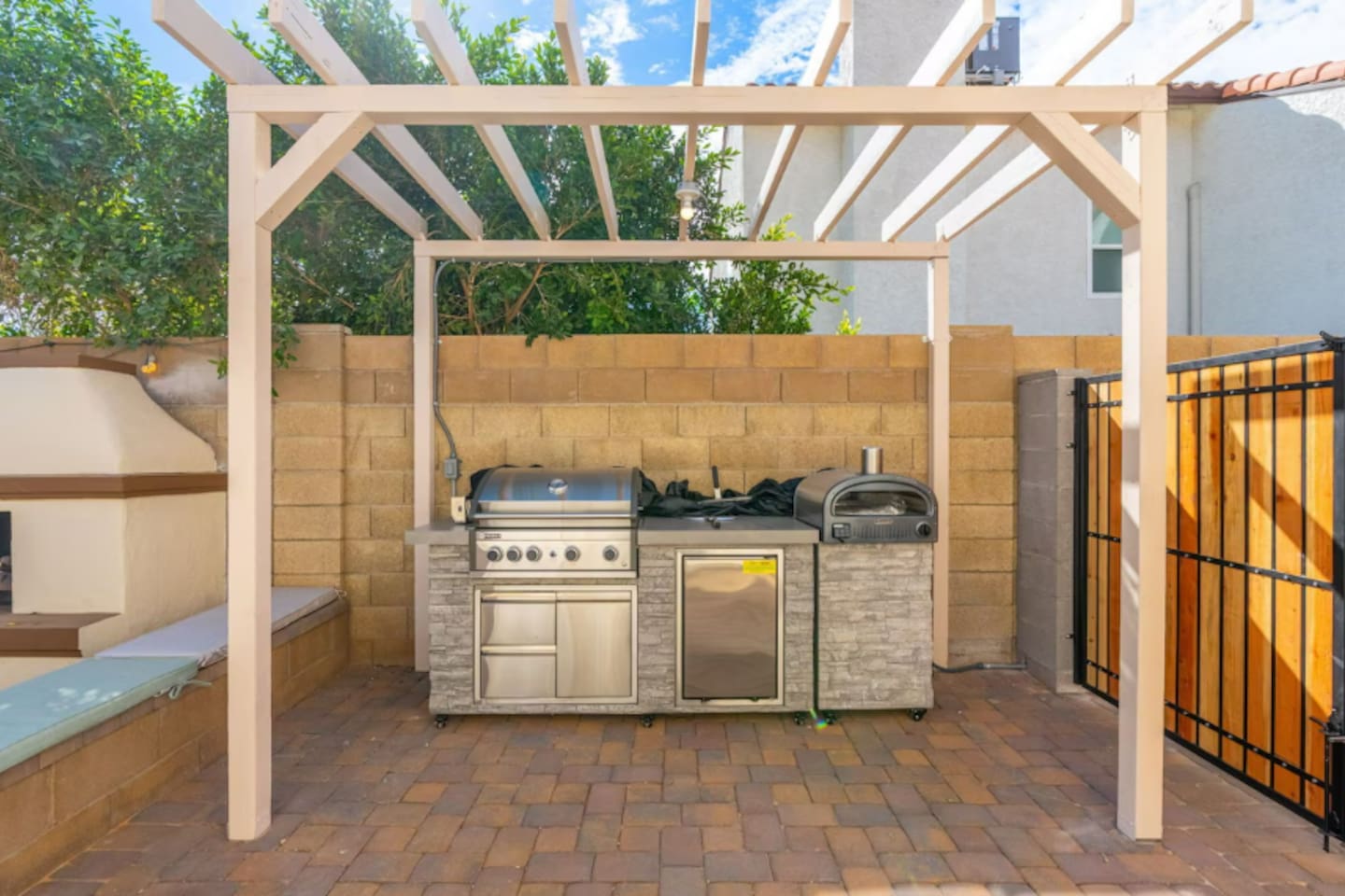Outdoor kitchen with pergola, built-in grill, pizza oven, and stone finishes—fully equipped for chef-level outdoor cooking.