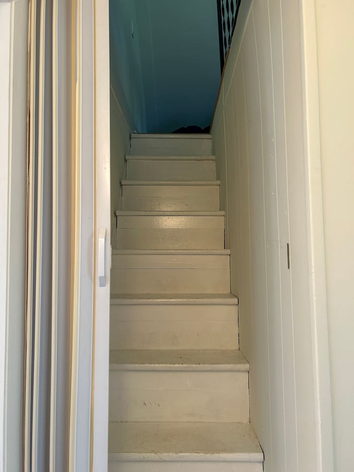 Stairs leading up to the bonus room for kids, with 3 twin beds. Note the steep, narrow staircase and accordion door. 