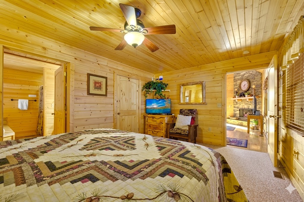 Bedroom #1 - Wake up to the charm of cabin living with a peek into the inviting living room beyond. A perfect space to unwind, catch a show, or simply enjoy the quiet hum of the mountains.