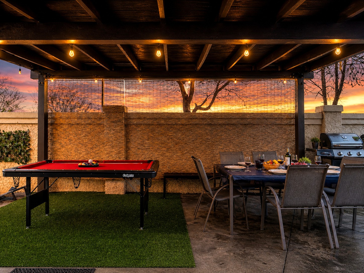Pool table and dining table under a covered patio, adjacent to the grill—perfect for group gatherings