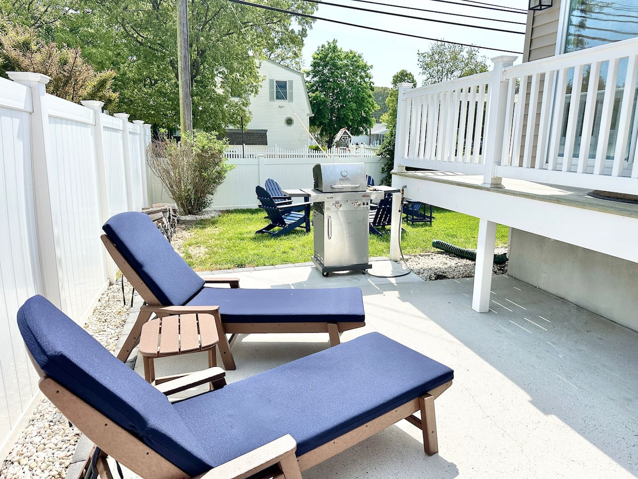 Enjoy the perfect outdoor setup for relaxation and dining. This fenced-in backyard features comfortable lounge chairs for soaking up the sun, a stainless steel grill for afternoon cookouts, and a grassy area with additional seating for the whole group.