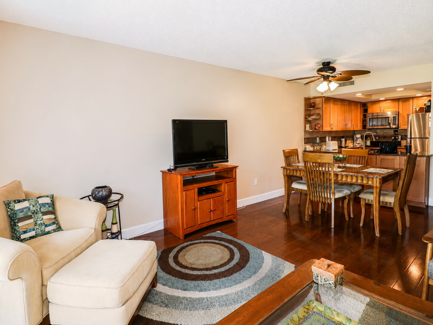 Inviting open layout with beige armchair, wood dining table, and modern kitchen.