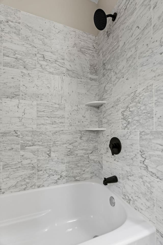 A newly installed, modern tiled shower/tub combo with a fresh and stylish design.