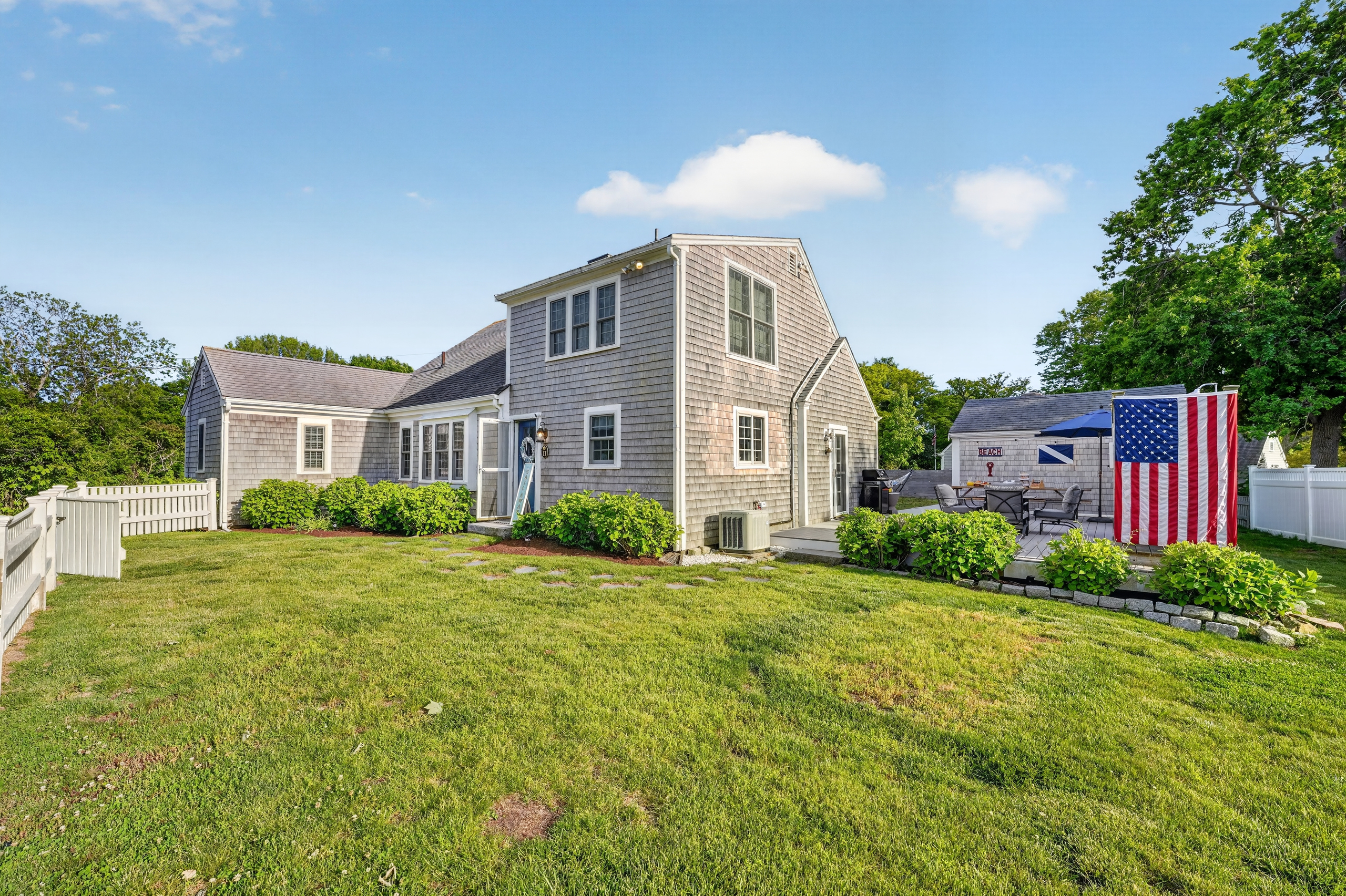 Beautiful exterior view showcasing the home's spacious yard, classic Cape Cod charm, and inviting outdoor spaces.
