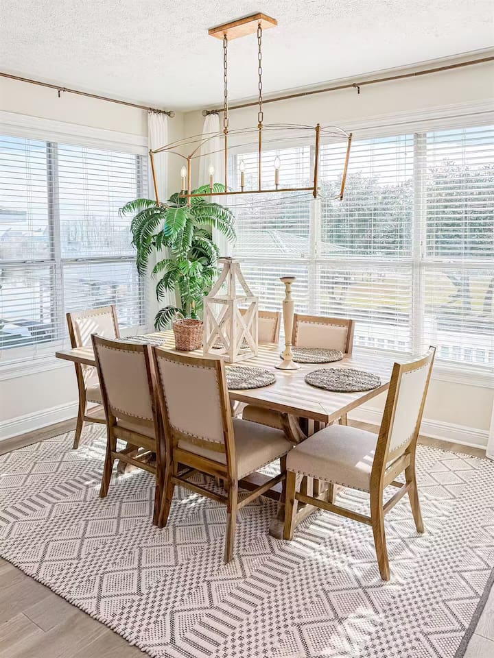 Sun-filled dining area with a spacious table for gatherings, stylish lighting, and large windows that flood the space with natural light—perfect for shared meals and conversations.