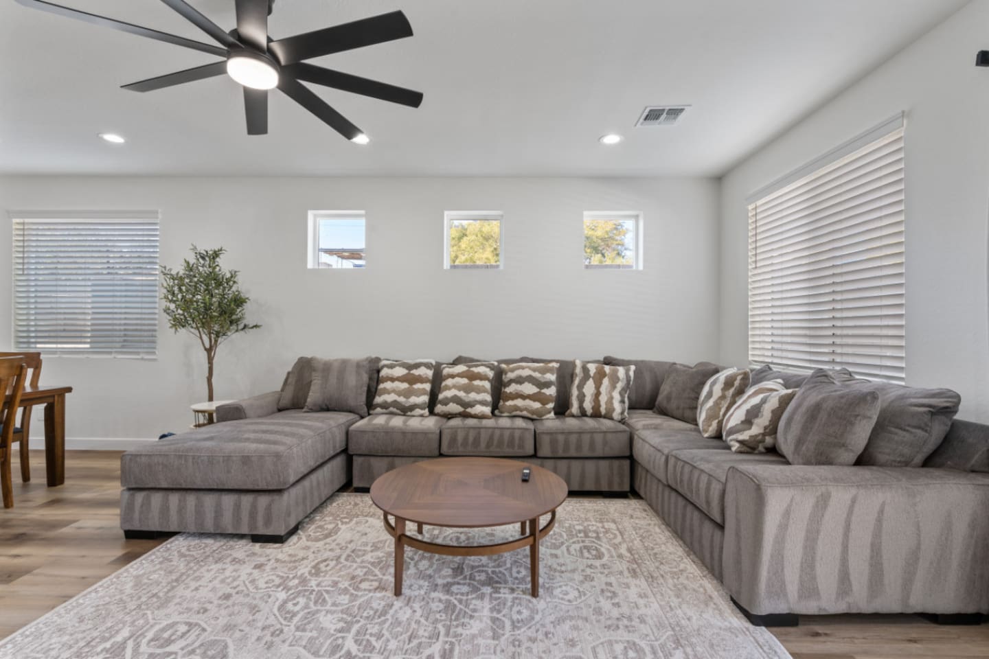 Living room with oversized sectional seating, ceiling fan, natural light, and plenty of space to relax or gather.