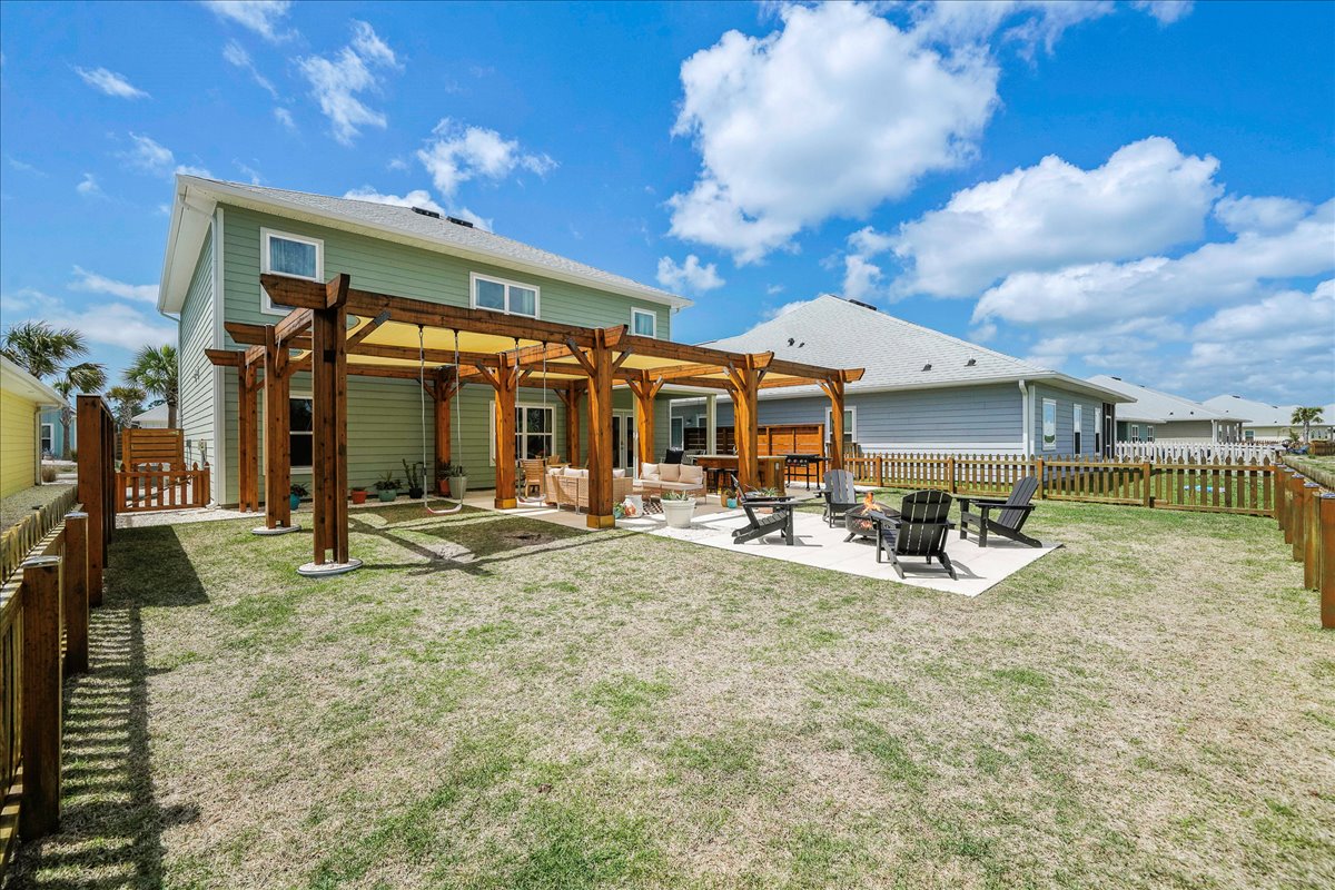 Enjoy outdoor living in this spacious fenced backyard with a fire pit, grill, comfortable seating, and a relaxing swing