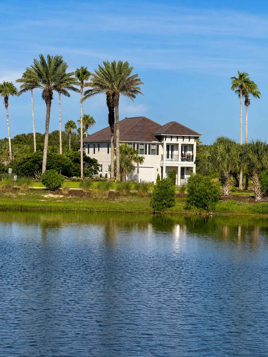 Mirrored in the still lake and crowned by towering palms, your home rests in a pocket of pure serenity. This is the backdrop for your family's week—peaceful water, rustling fronds, and the sense that here, at last, everyone can finally relax.