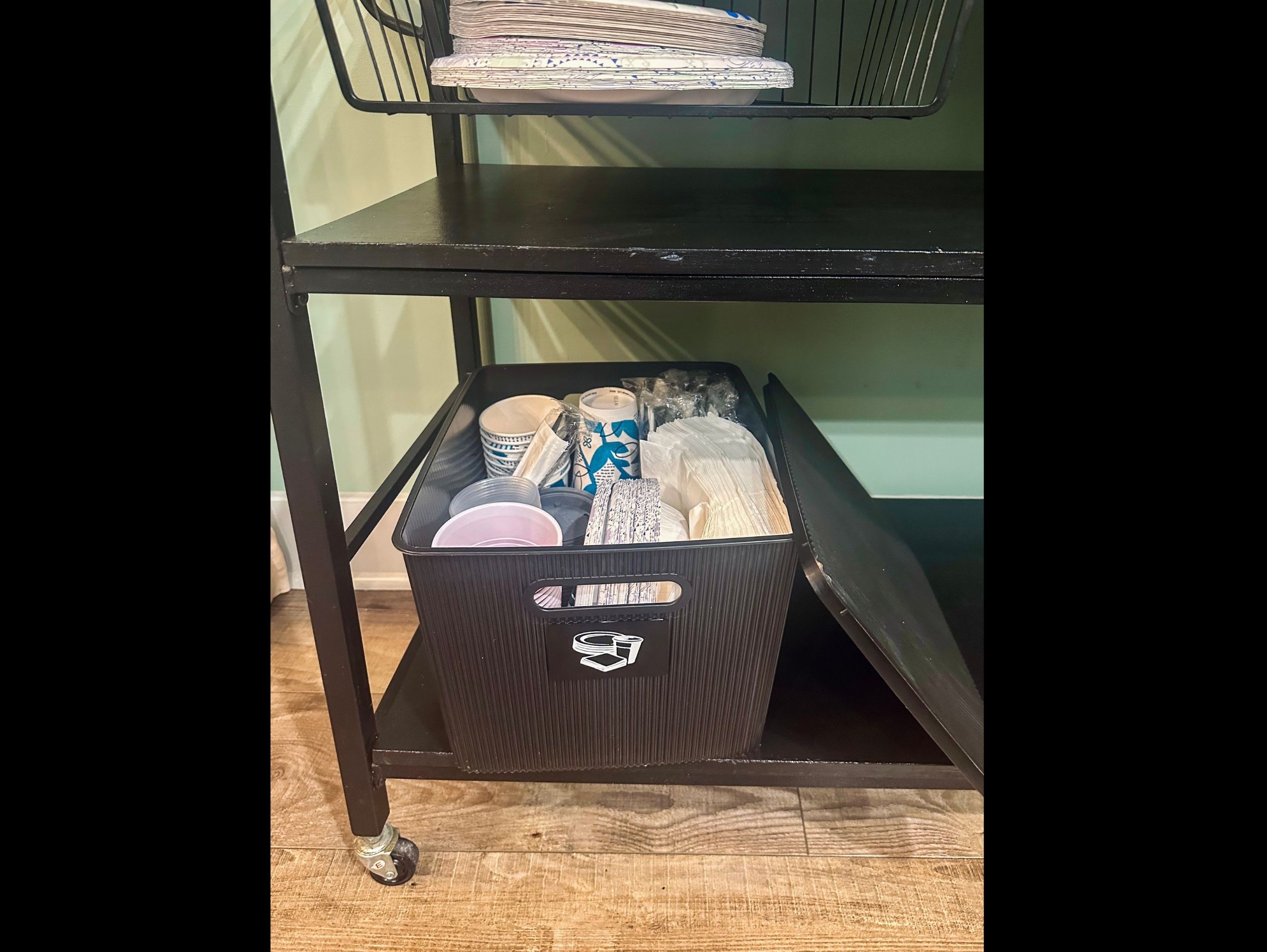 Under-cart kitchen storage stocked with disposable essentials including paper plates, plastic cups, napkins, and utensils for added convenience.