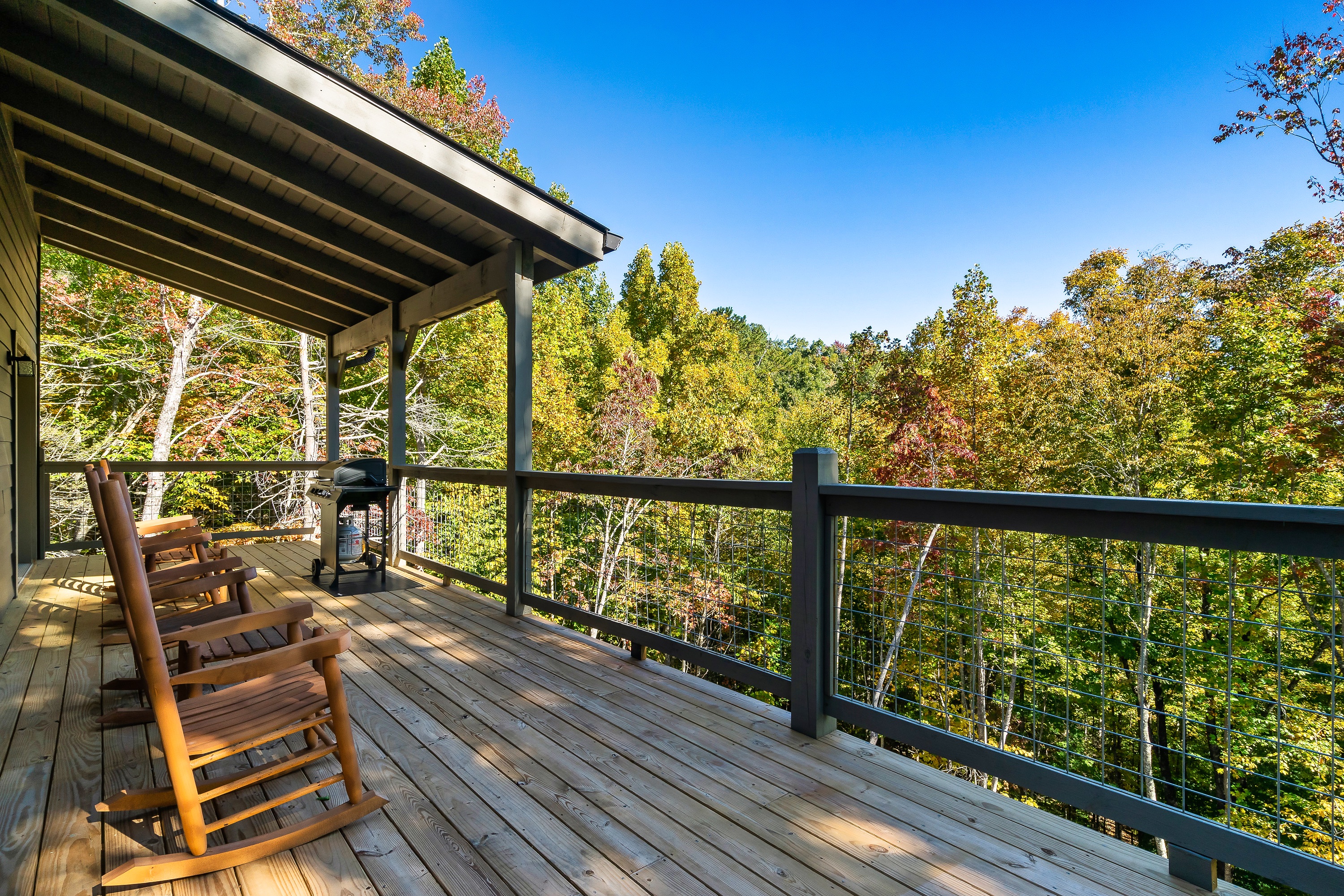 Rocking chairs, a gas grill, and peaceful wooded views await on the covered deck.