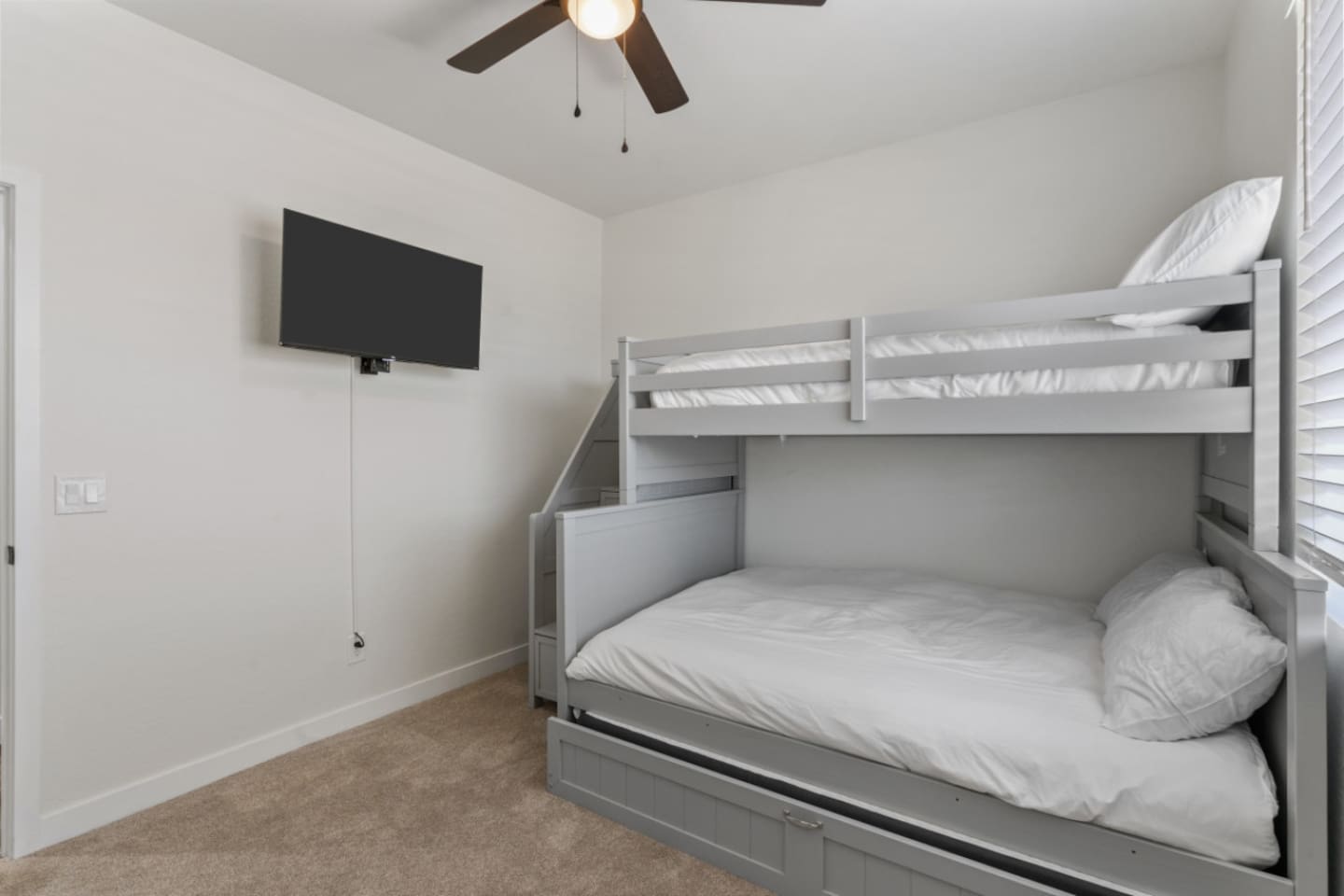 Guest Bedroom 3 with bunk-style sleeping, trundle bed, ceiling fan, and a flexible setup for kids or extra guests.