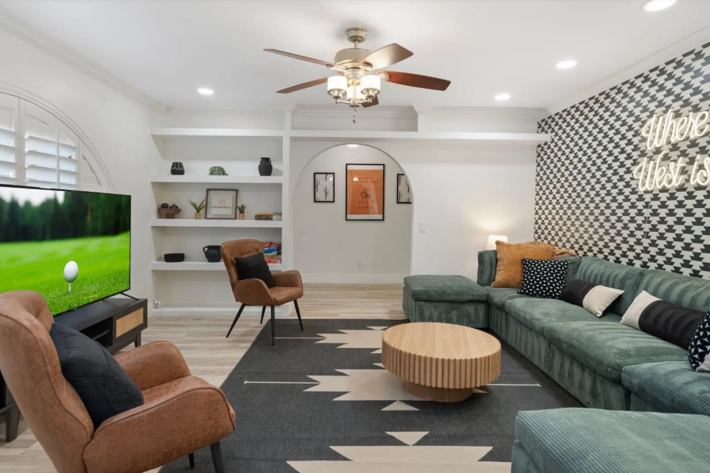 Sink into the deep green sectional and let the evening unwind. Desert-inspired art peeks through the archway, a bold houndstooth wall sets the mood, and the neon glow overhead makes it clear this room was made for gathering.