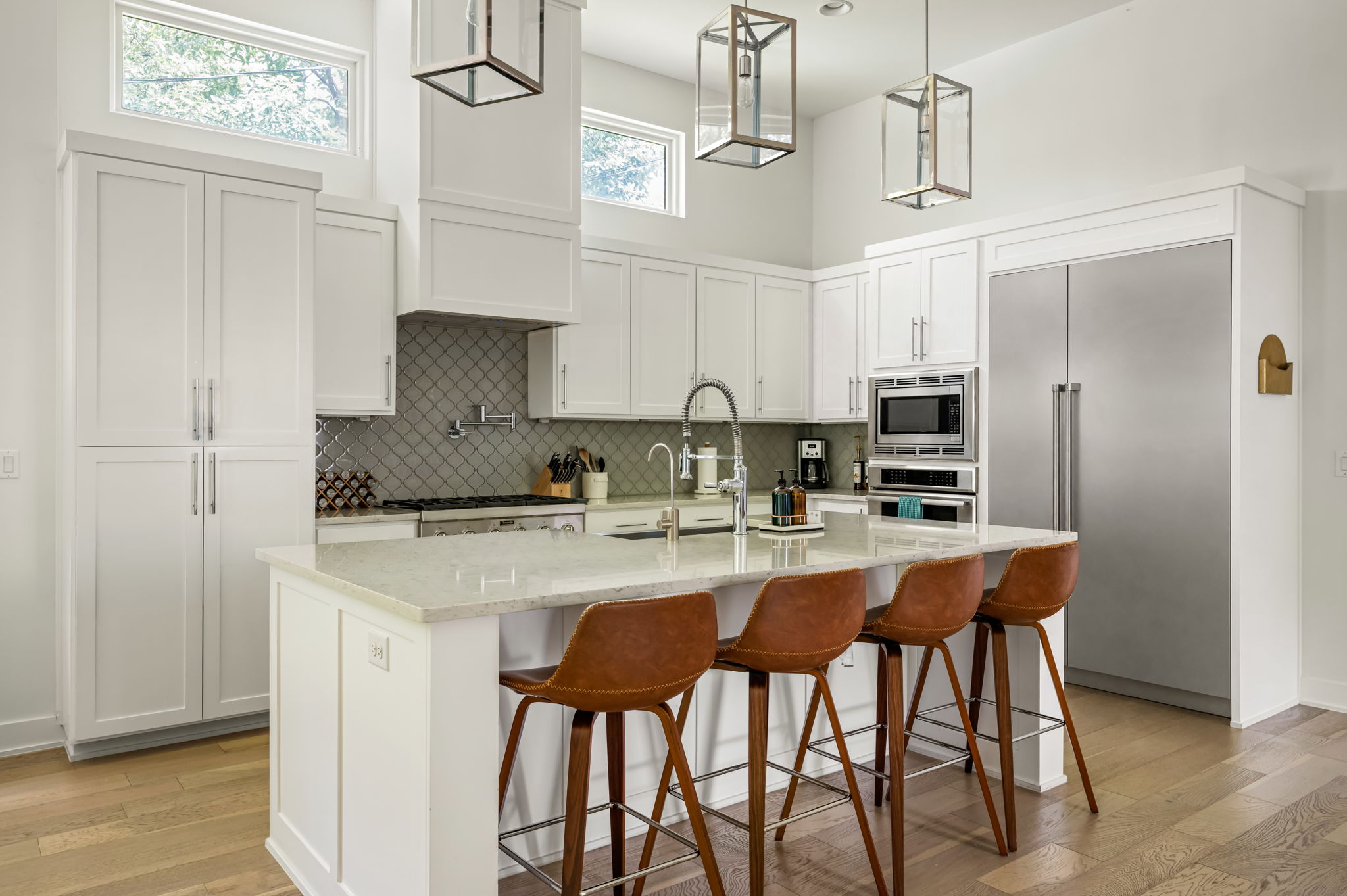 Chef's dream kitchen with a massive quartz island, leather bar stools, and stainless steel appliances — designed for entertaining and everyday living