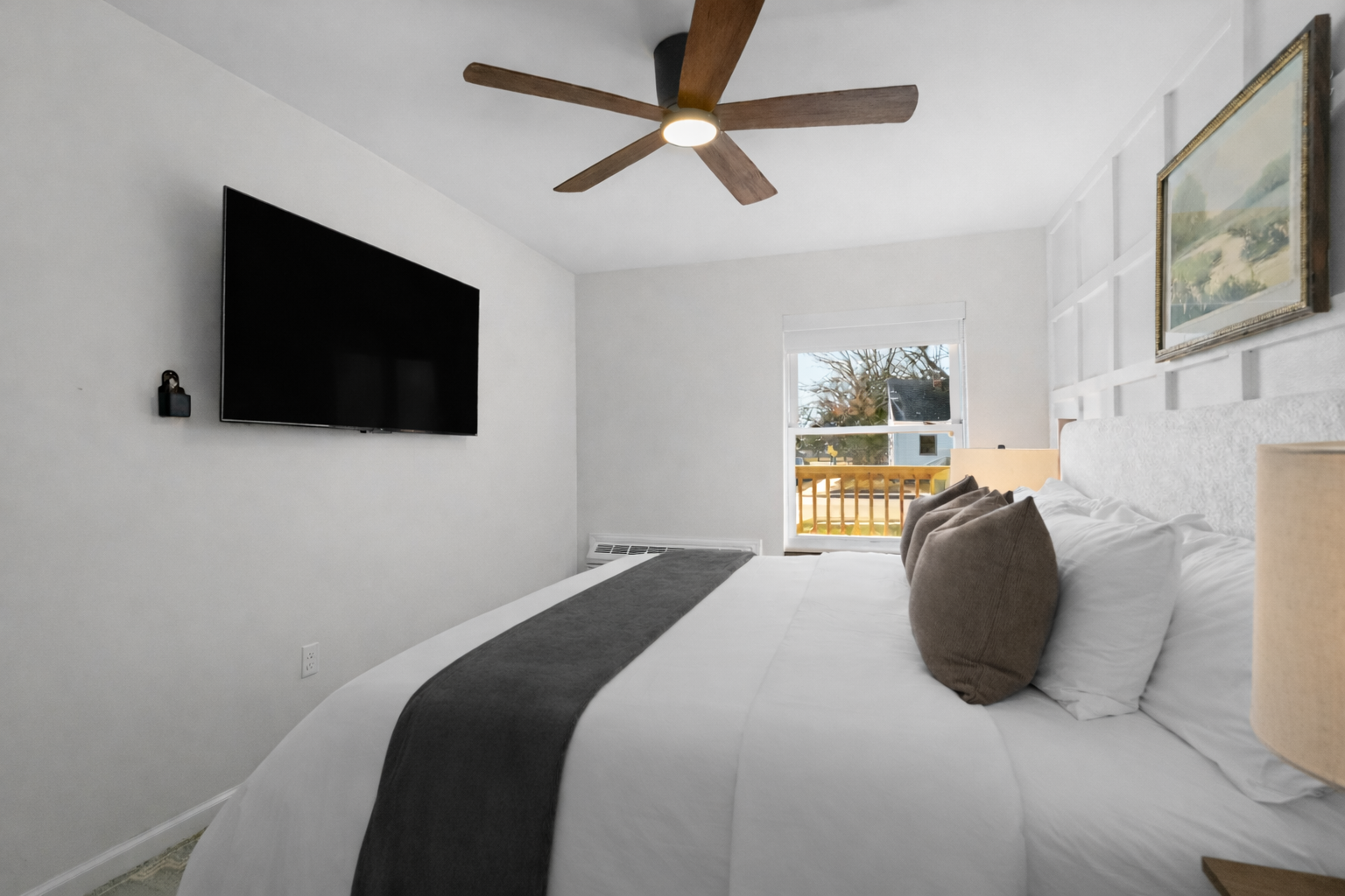 Peaceful bedroom with plush bedding, ceiling fan, and wall-mounted TV—designed for restful nights and a relaxing, comfortable stay.
