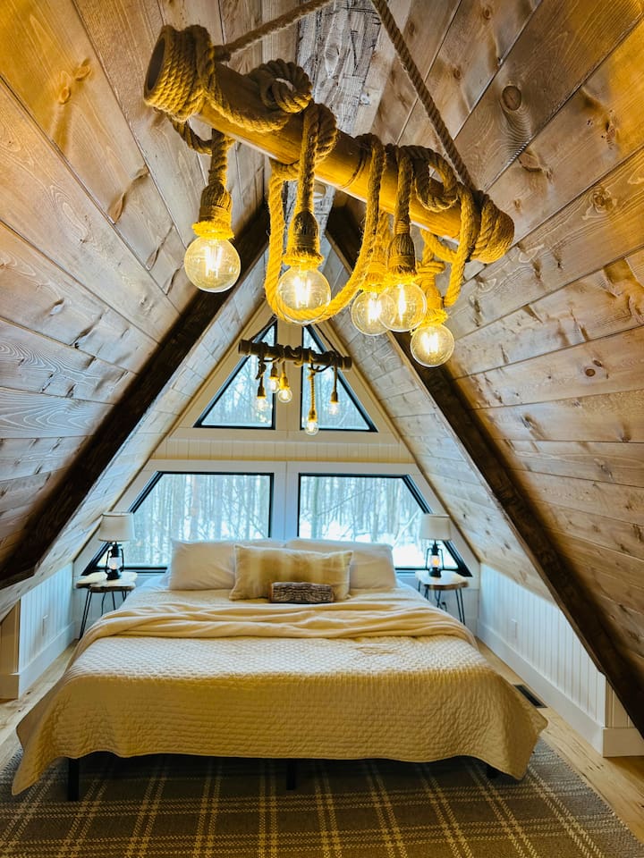 This dreamy second-story loft is accessible only by a ship’s ladder, adding an adventurous yet intimate feel. It features a king bed beneath a dramatic A-frame ceiling. Large triangular windows offer stunning views, making it the perfect hideaway.
