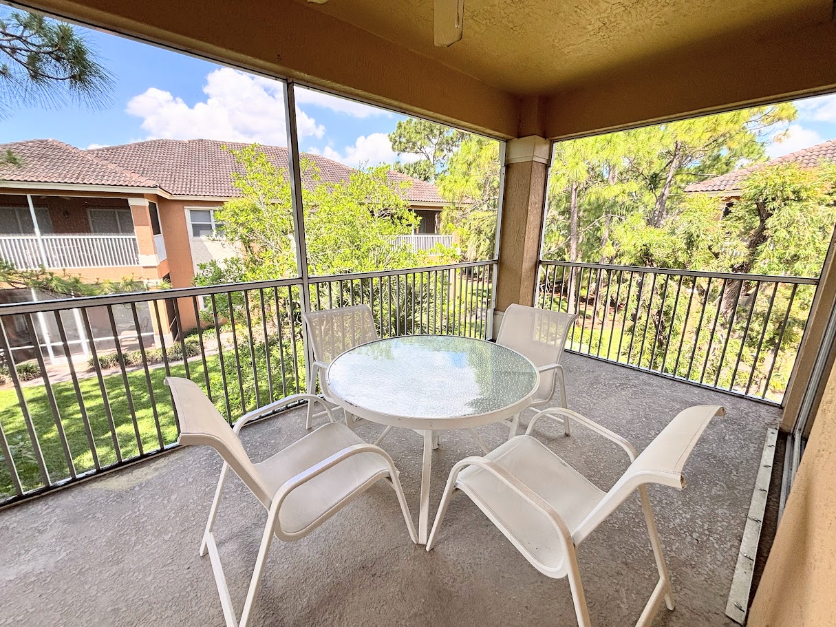 Private screened balcony with outdoor seating, offering a peaceful spot to relax and enjoy the surrounding greenery.